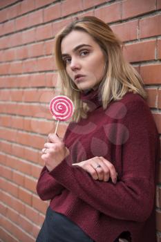 girl with candy near a brick wall