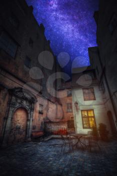 Astrophotography, starry sky shines at night. Vintage retro travel image of a narrow medieval street in old town Riga