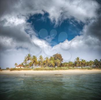 Goa beach with palm trees and clouds in the shape of heart