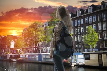 girl tourist with a backpack looking at the sunset in Amsterdam