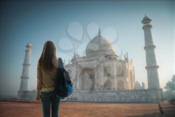 girl traveler stands with a backpack in the background of the Taj Mahal