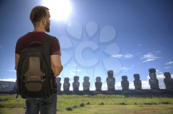 man traveler stands with a backpack on the background of Easter Island statues