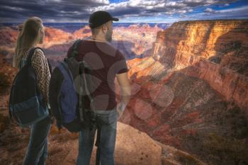 girl with a male traveler stands with backpacks on the background of the Grand Canyon, USA