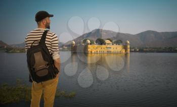 tourist traveler with a backpack stands on the background of the Water Palace. Jaipur.