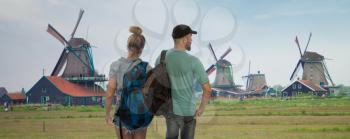A married couple of tourists travel around the Netherlands.Traditional Dutch windmills with canal near the Amsterdam, Holland