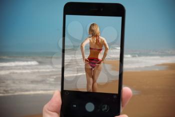   videobloger takes pictures on a smartphone. girl on the beach at sunset. Relax by the water