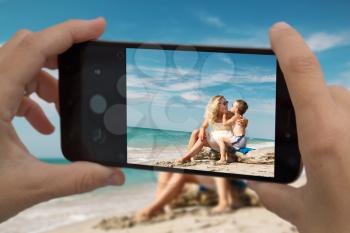 Dad takes his wife and son to a smartphone on a family vacation by the sea.