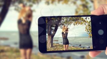 blogger takes pictures of a girl by the sea on a smartphone