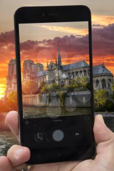  videobloger takes pictures on a smartphone sunset Notre Dame de Paris. France. Europe