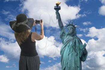 Girl traveler takes pictures of the statue of freedom. USA.