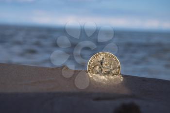bitcoin on the beach in the sand against the sea