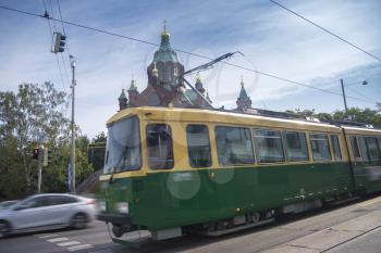 on the streets of Helsinki there is a tram in the background  Uspenski Cathedral. 