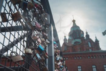 Hanging locks on the bridge on the background of the Uspensky Cathedral of Helsinki