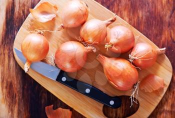 raw onion on wooden board and on a table