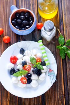 mozzarella cheese with tomato and olives on plate