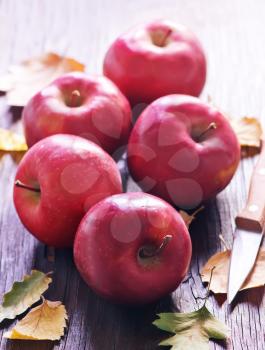 red apples and knife on the wooden table