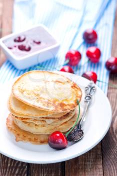 pancakes with cherry on the plate and on a table