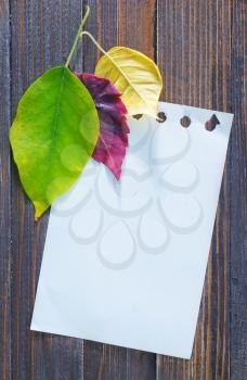 autumn leaves on the wooden background,yellow leaves and notepad