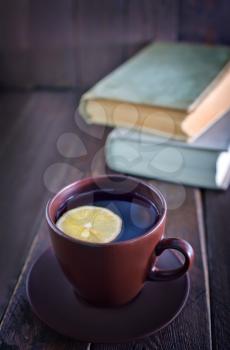 tea with lemon in cup and old books