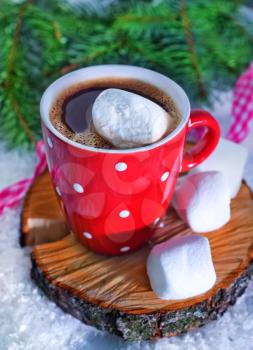 cocoa drink with marshmallows in cup and on a table