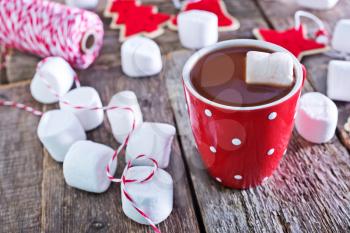 cocoa drink with marshmallows in cup and on a table