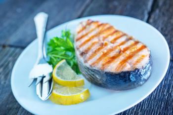 grilled salmon steak with lemon on white plate