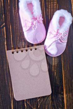 baby shoes and notepad for note on a table