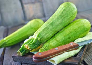 raw zucchini on wooden tray and on a table