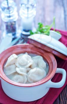 boiled pelmeni in bowl and on a table