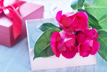 box for present and red roses on a table