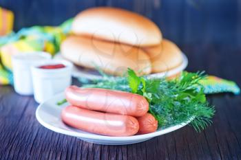 buns and sausages on white plate and on a table
