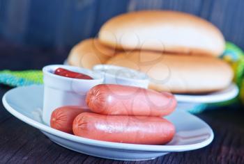 buns and sausages on white plate and on a table