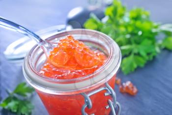 red salmon caviar in glass bank and on a table