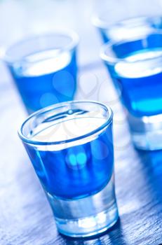 blue alcoholic drink into small glasses on a table