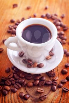 fresh coffee in the white cup, coffee beans on wooden background