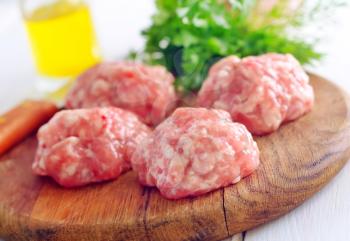 Raw balls from meat on wooden background