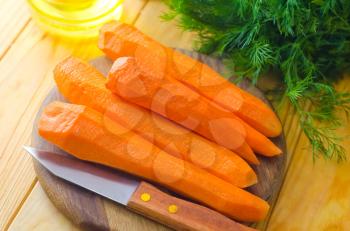 raw carrots and knife on the wooden board