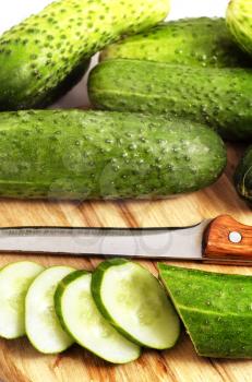 Fresh cucumber and knife on wooden board