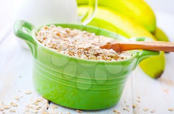 Oat flakes in the green bowl with banana and milk