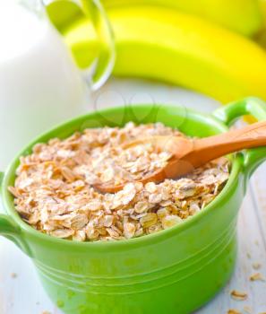 Oat flakes in the green bowl with banana and milk
