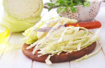 Raw cabbage and knife on the wooden board