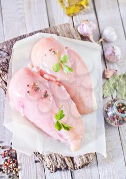 raw chicken fillet on board and on a table