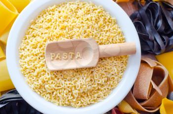 assortment of raw pasta and wheat on wooden background