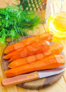 raw carrots and knife on the wooden board