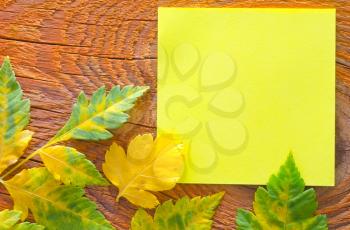 note and leaves on wooden background