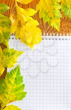 note and leaves on wooden background
