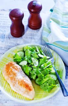 chicken breast with salad on plate and on a table