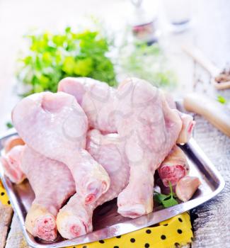 raw chicken legs on metal tray and on a table