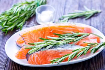 fresh salmon with rosemary on plate and on a table