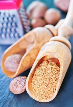 nutmeg spice in wooden spoon and on a table